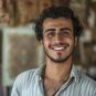 ai-generated-a-young-man-from-the-middle-east-with-a-proud-expression-and-a-piece-of-art-is-showcasing-his-work-in-a-gallery-in-tehran-iran-photo